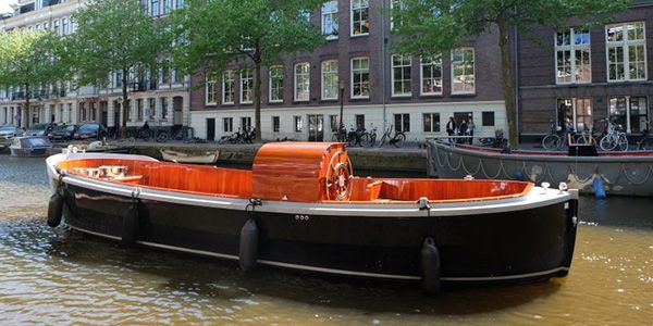 Moderne open sloep Een moderne open sloep varend door de Amsterdamse grachten