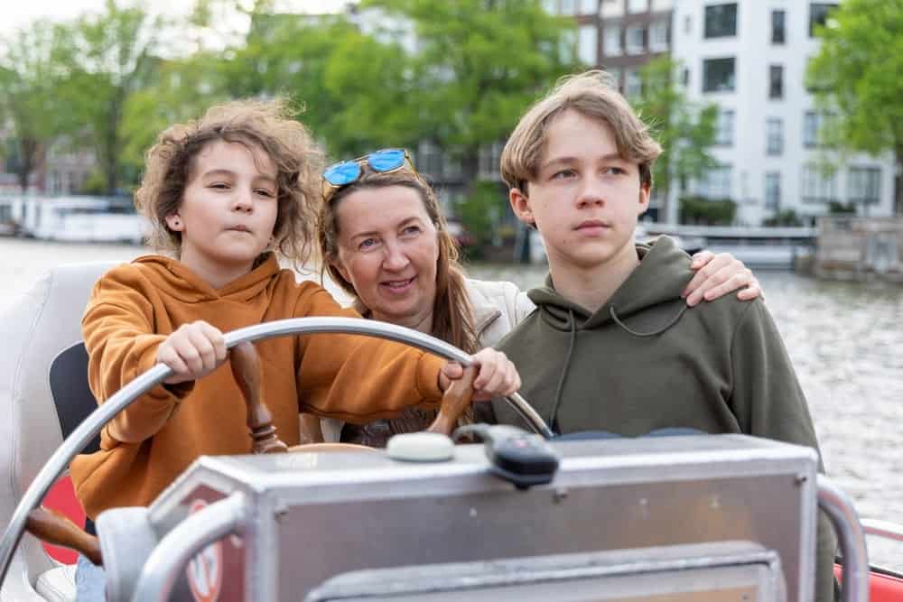 Ouder met tieners op een boot in Amsterdam