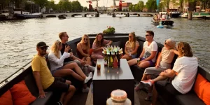 Eine Gruppe Menschen auf einer Schaluppe mit Getränken bei Sonnenuntergang