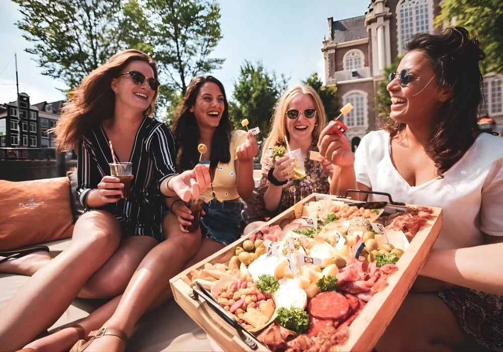 Four women eating from a snack platter on a boat in Amsterdam