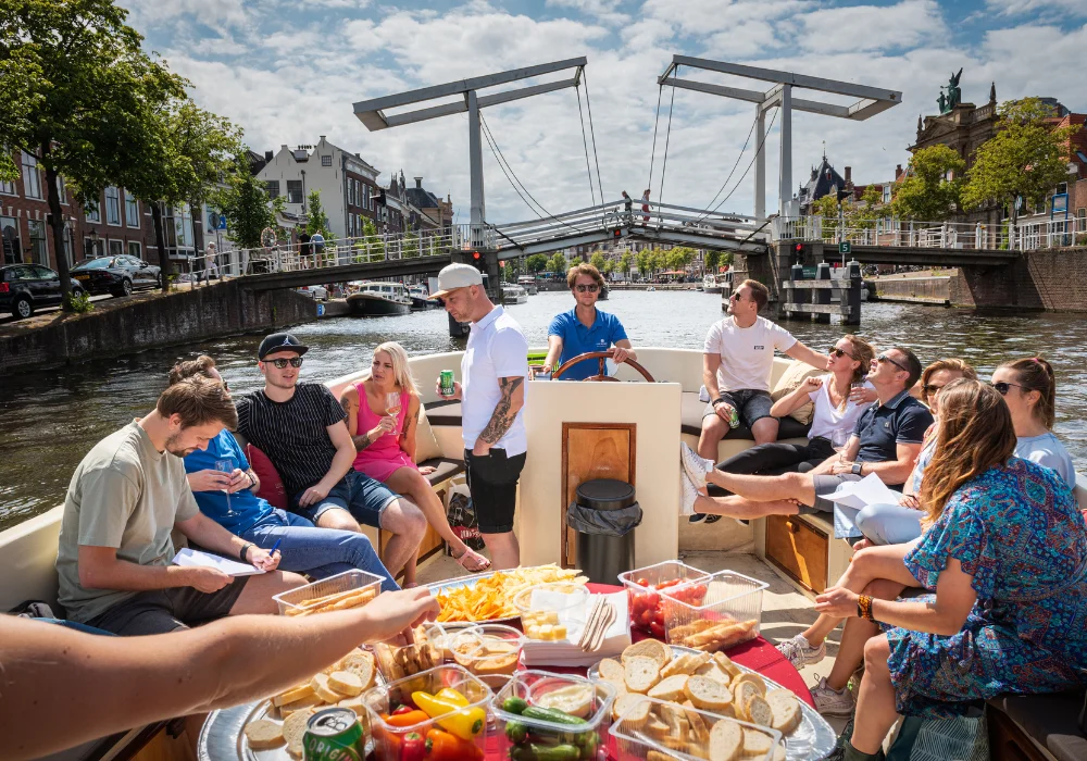 Groep mensen op een sloep in Haarlem met een borrelplank