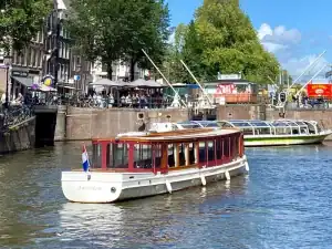 Salonboot Iris varend voor Amsterdamse brug