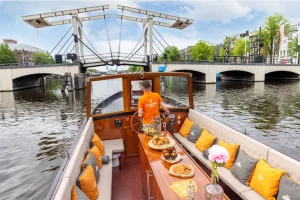 Kapitän auf dem Bartolotti-Boot unter einer Brücke in Amsterdam