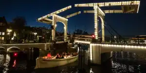 Sloep vaart 's avonds onder de verlichte Magere Brug