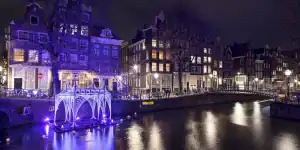 Paars lichtkunstwerk op de gracht tijdens het Amsterdam Light Festival