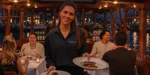 Gastvrouw serveert het diner in een verlichte salonboot op de grachten