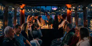Volle salonboot met een groep aan de borrel op de grachten 's avonds